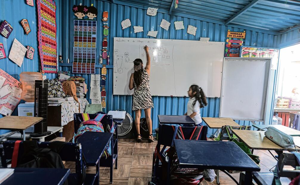 La profesora Samantha Ramírez prepara el pizarrón para la lección del día y el material que se utilizará, mientras los niños llegan de la clase de educación física. Foto: Gabriel Pano / EL UNIVERSAL